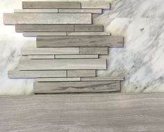 a white marble wall and floor with grey wood planks in the middle, as well as several different types of tiles