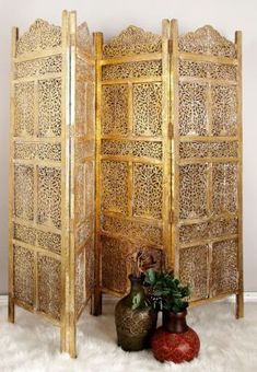 an ornate wooden room divider with two vases on the floor next to it