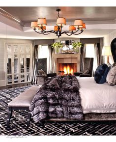 a bedroom with a fireplace in the middle and lots of pillows on the bed next to it