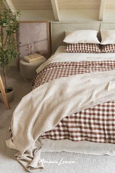 a bed with brown and white checkered comforter on it's side, next to a potted plant