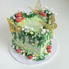 a green cake decorated with flowers and butterflies