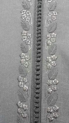 a close up view of the zippers on a grey jacket with flowers and leaves