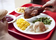 a person is cutting into a piece of meat on a plate with corn and green beans