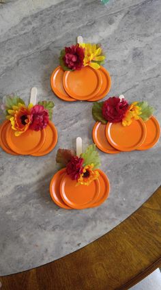 four orange plates with flowers on them sitting on top of a marble table next to candles