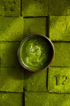 a green substance in a red bowl on a brick wall