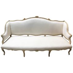 a white couch with gold trimmings on it's arms and back legs