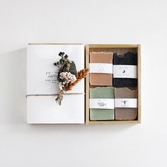 an open box filled with different types of soaps and flowers on top of a white wall