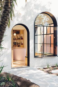 an open door leading to a bathroom with a tub in the doorway and palm trees outside