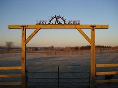 a wooden gate with the word lake horse on it's side in front of an open field