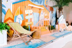 a beach scene with a lawn chair and surfboards on the display wall, in front of a potted palm tree