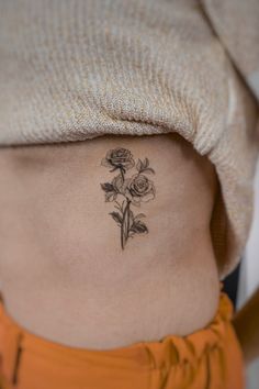 a woman's stomach with a small flower tattoo on her lower side ribcage