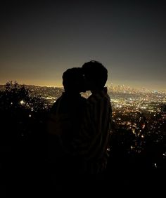 two people standing in front of a city at night with their backs to each other