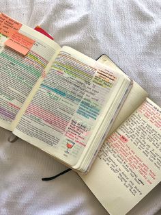 an open book with sticky notes attached to it on top of a white bed sheet