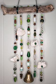 a wall hanging made out of different kinds of beads and glass items on a wooden stick