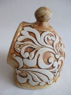 a ceramic vase with an ornate design on it's side, sitting on a white surface