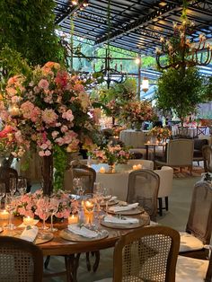 a dining room filled with lots of tables covered in floral centerpieces and lit candles