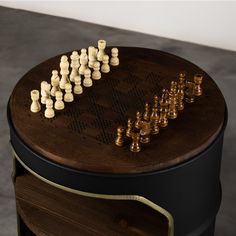 a wooden chess set on top of a black and brown table next to a white wall