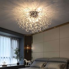 a large bed sitting under a chandelier in a bedroom next to a window