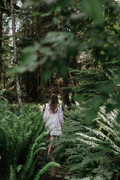 a woman walking through ferns in the woods