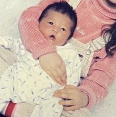 a woman holding a baby in her arms and looking at the camera with an expression on her face