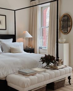 a white bed sitting next to a window in a bedroom