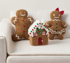 two gingerbread house ornaments sitting on a couch with one gingerbread man in the middle