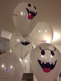 white balloons with faces drawn on them in the shape of mouths and teeth, hanging from a ceiling