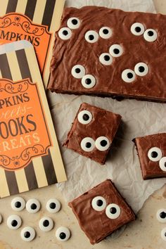 chocolate treats with googly eyes on them next to an orange book and some candy