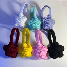 six crocheted purses are lined up on a white surface, each with different colors