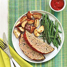 a white plate topped with meat, potatoes and green beans next to a knife and fork