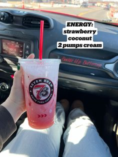 a person holding a drink in their hand while sitting in the driver's seat of a car