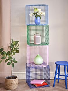 three shelves with plants and vases on them in front of a potted plant