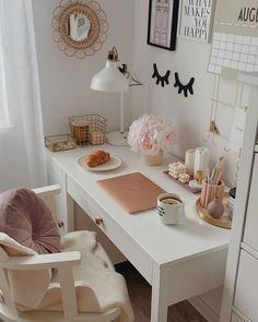 a white desk topped with a laptop computer sitting next to a chair and table covered in pink flowers