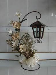 a lamp hanging from the side of a wall next to flowers