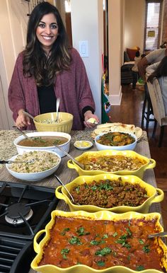 a woman standing in front of a table filled with different types of food and dishes