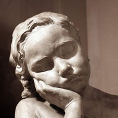 a statue of a young boy with his hands on his face, resting his chin on his hand