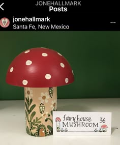 a red mushroom sitting on top of a table next to a sign that says,