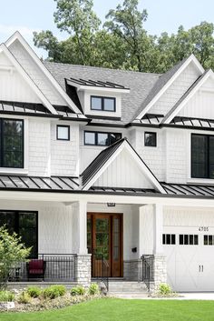 a large white house with black trim on the roof and windows, along with two car garages