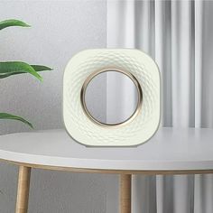 a white table with a round mirror on it next to a potted green plant