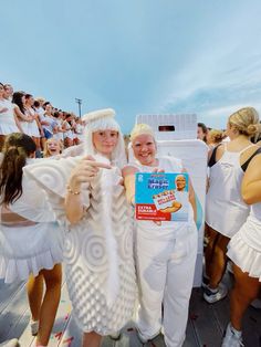 two women dressed in white standing next to each other holding up a box of cereal