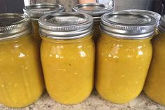 four jars filled with yellow liquid sitting on top of a counter