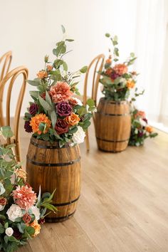 three wooden vases filled with flowers sitting on top of a wooden floor next to chairs