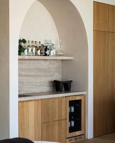 a kitchen with an arch in the wall and bottles on the counter top above it