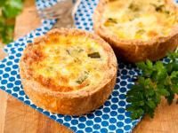 two quiche pies sitting on top of a blue and white napkin with parsley