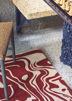 a table with chess pieces on it in front of a rug and chair next to the table