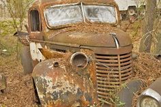 an old rusted out truck sitting in the woods