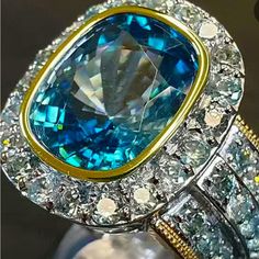 Blue Topaz Statement Two-Tone With Three Side Rows And Hallow Zircon On Cigar Band Cocktail Ring All My Rings I Am Able To Sell At A Affordable Price Because I Believe Everyone Deserves A Little Bling This Is An Exceptional Piece Dazzling Blue Topaz Ring With Halo Setting, Light Blue Aquamarine Jewelry With Diamond Accents, Light Blue Topaz Jewelry With Halo Setting, Light Blue Halo Setting Blue Topaz Jewelry, Luxury Light Blue Topaz Jewelry, Light Blue Topaz Jewelry With Center Stone, Blue Aquamarine Fine Jewelry, Blue Topaz Jewelry For Formal Occasions, Blue Aquamarine Jewelry With Center Stone