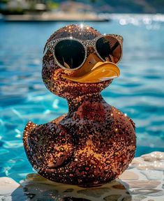 a rubber duck wearing sunglasses and sitting on the edge of a swimming pool with water in the background