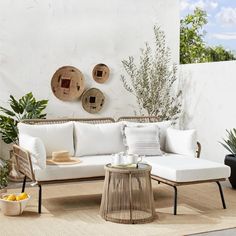 a white couch sitting on top of a wooden floor next to a table and potted plants