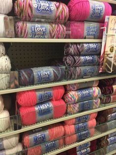 many skeins of yarn are on shelves in a store, and there is also a sign that says i love yarn